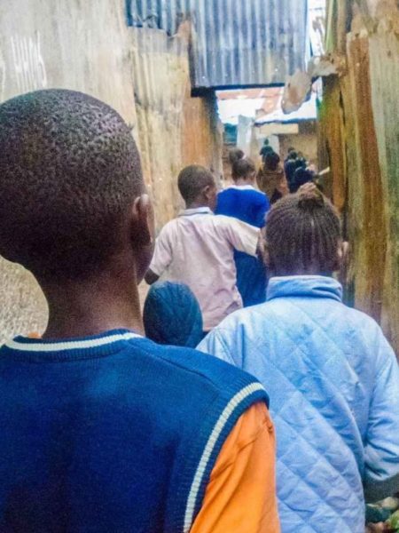 Kinder gehen einen engen Gang in den Kiberia-Slums entlang